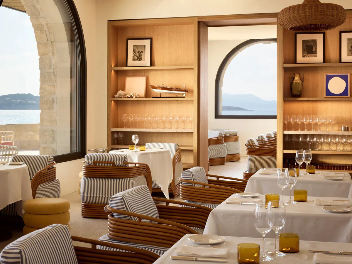 Dining room shelves hold curios and glassware between stone arches framing the sea