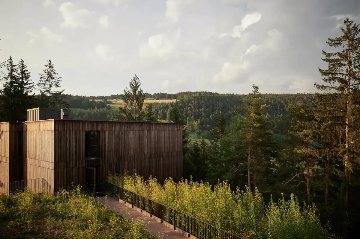 Wooden building set in rolling alpine meadows with surrounding spruce and larch trees