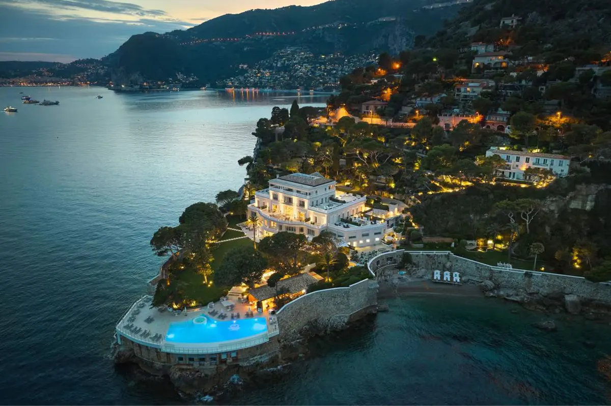 Aerial dusk view of the hotel on a hillside peninsula with lit buildings