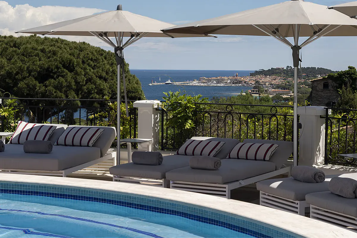 Shaded pool terrace with deep loungers under a cantilever overhang
