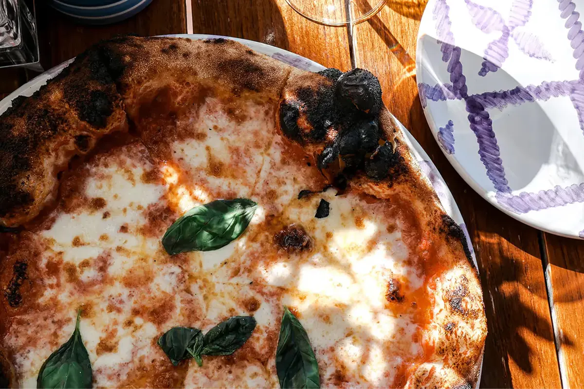 A personal-size pizza with cheese and basil leaf