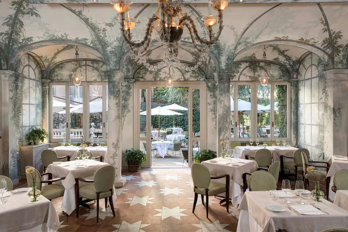 Elegant dining gallery with arched niches, columns, and fireplace beyond