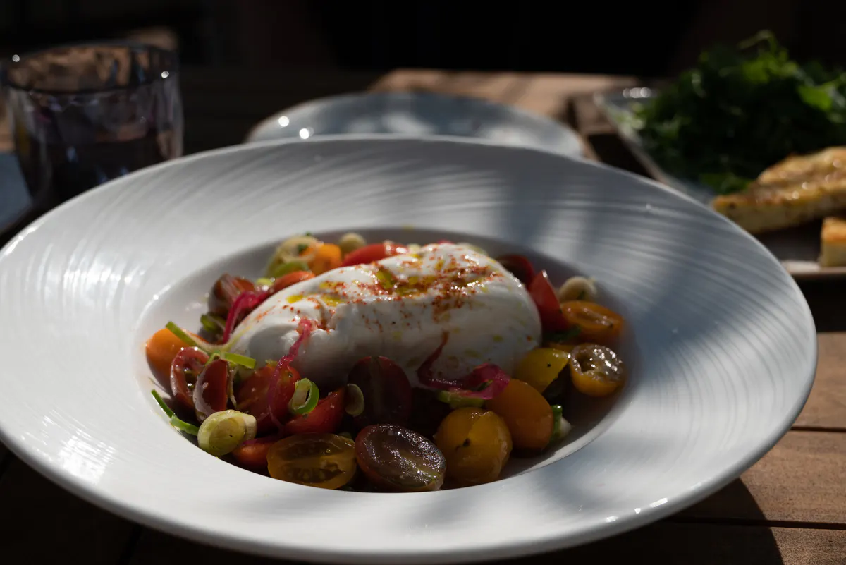 A plated dish with vegetables and seafood on a white plate at a coastal restaurant