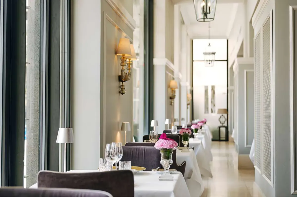 Long corridor with mirrors, wall sconces, and set dining tables
