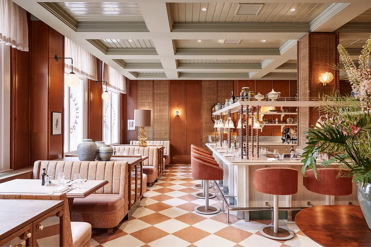 Bar seating area with burgundy paneling, warm lighting, and sophisticated glassware display