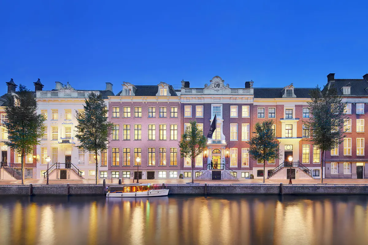 Illuminated historic facades reflected in the canal at dusk, brick palaces with gabled roofs and shuttered windows