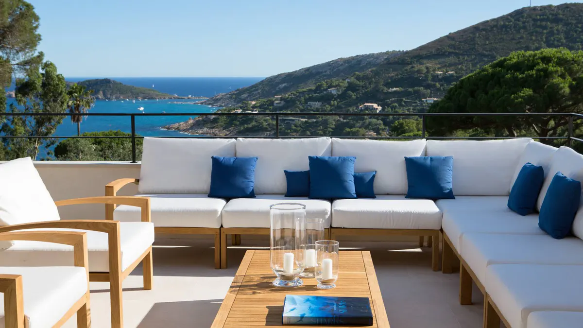 Terraced oceanside seating with cream cushions and blue throw pillows
