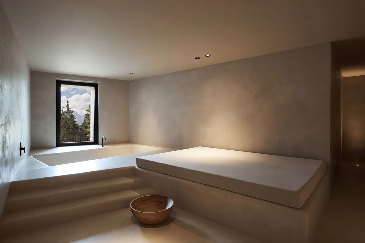 A spa treatment room with light wood and stone surfaces, minimal furnishings, and soft natural light