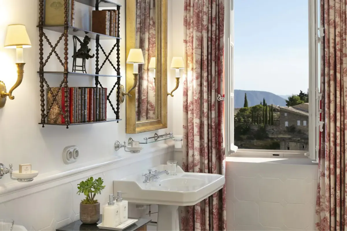 Bathroom with porthole mirror and shower door overlooking mountains