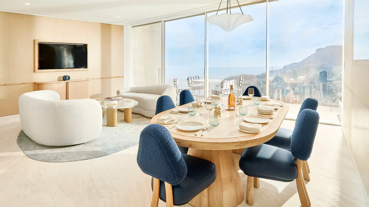 Suite with white cylindrical tub and dining area overlooking coastal landscape