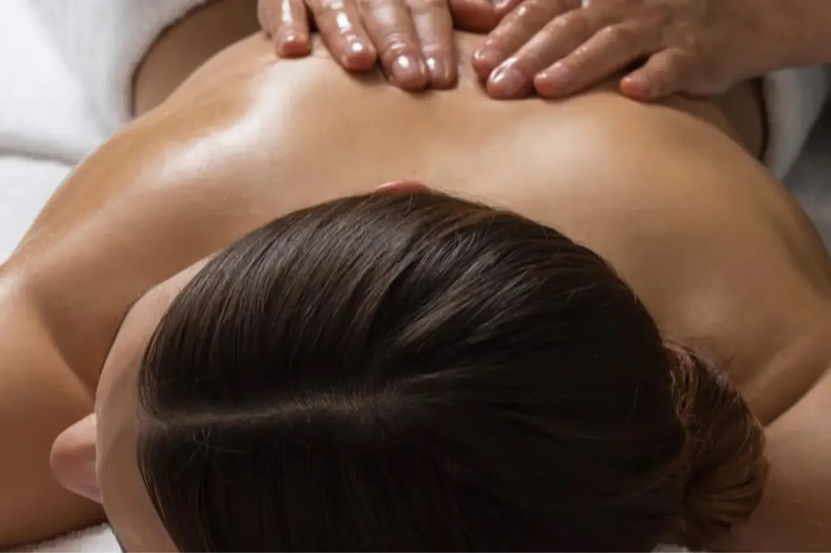 Back massage treatment in progress on white linens