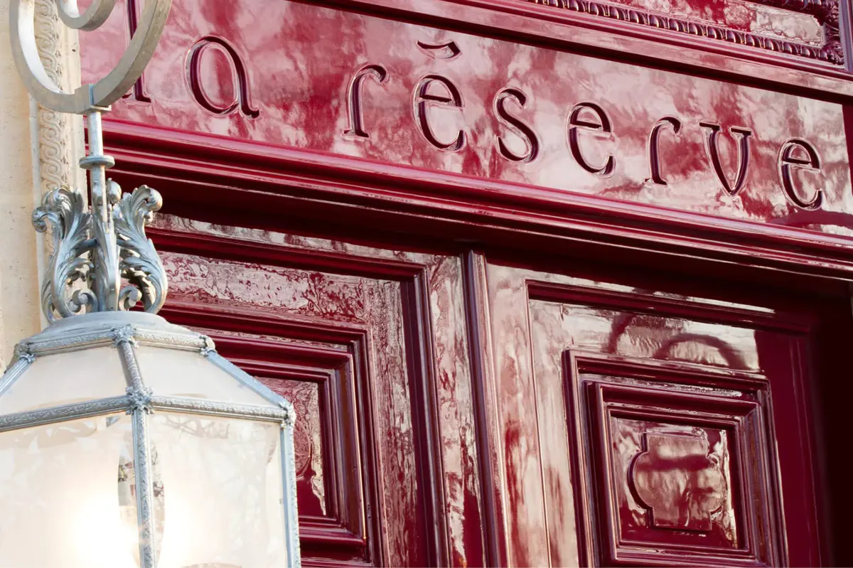 A closeup of the burgundy entrance door with the hotel name in script