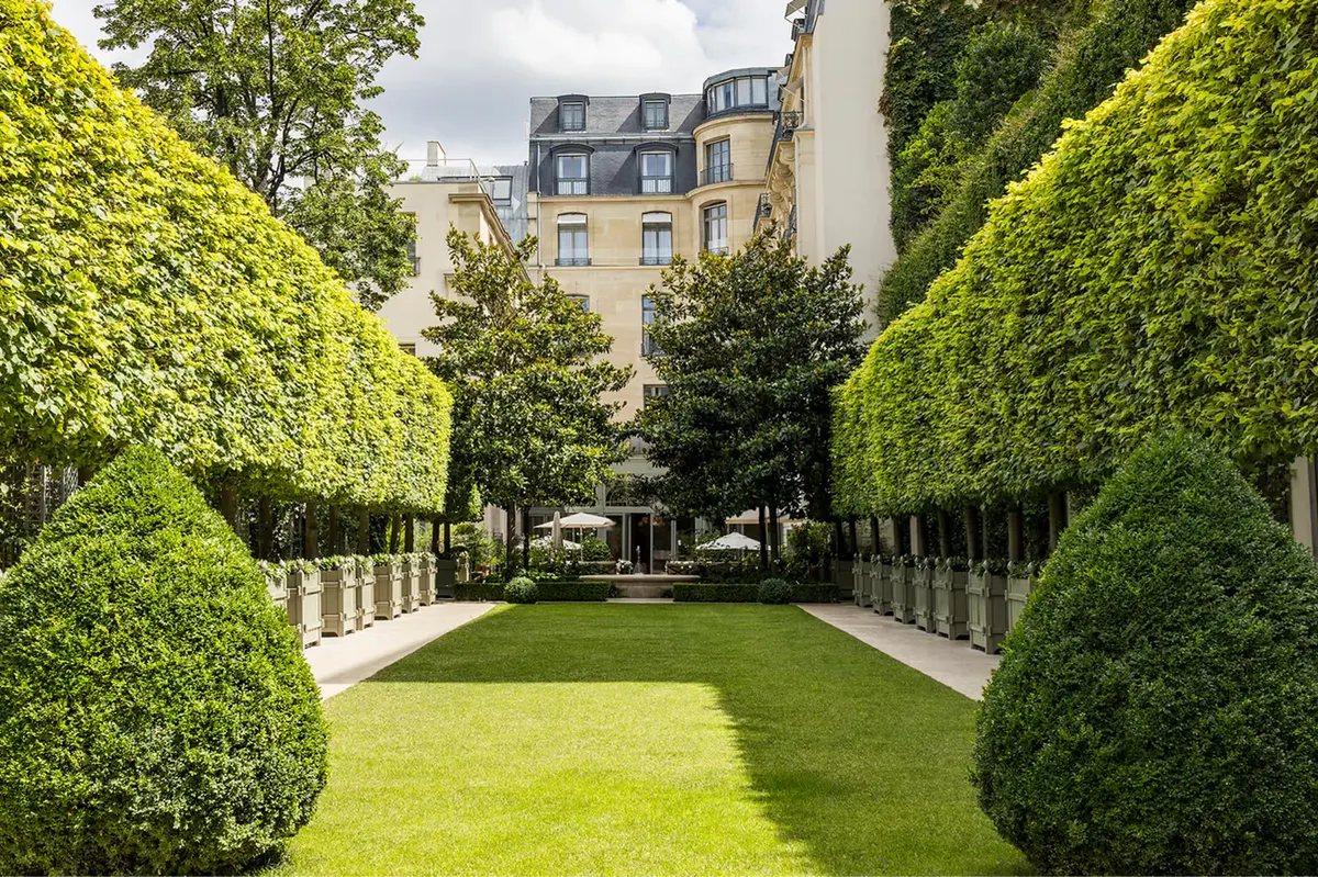 The private garden with sculptured hedges, white fencing, and views of the Paris facade