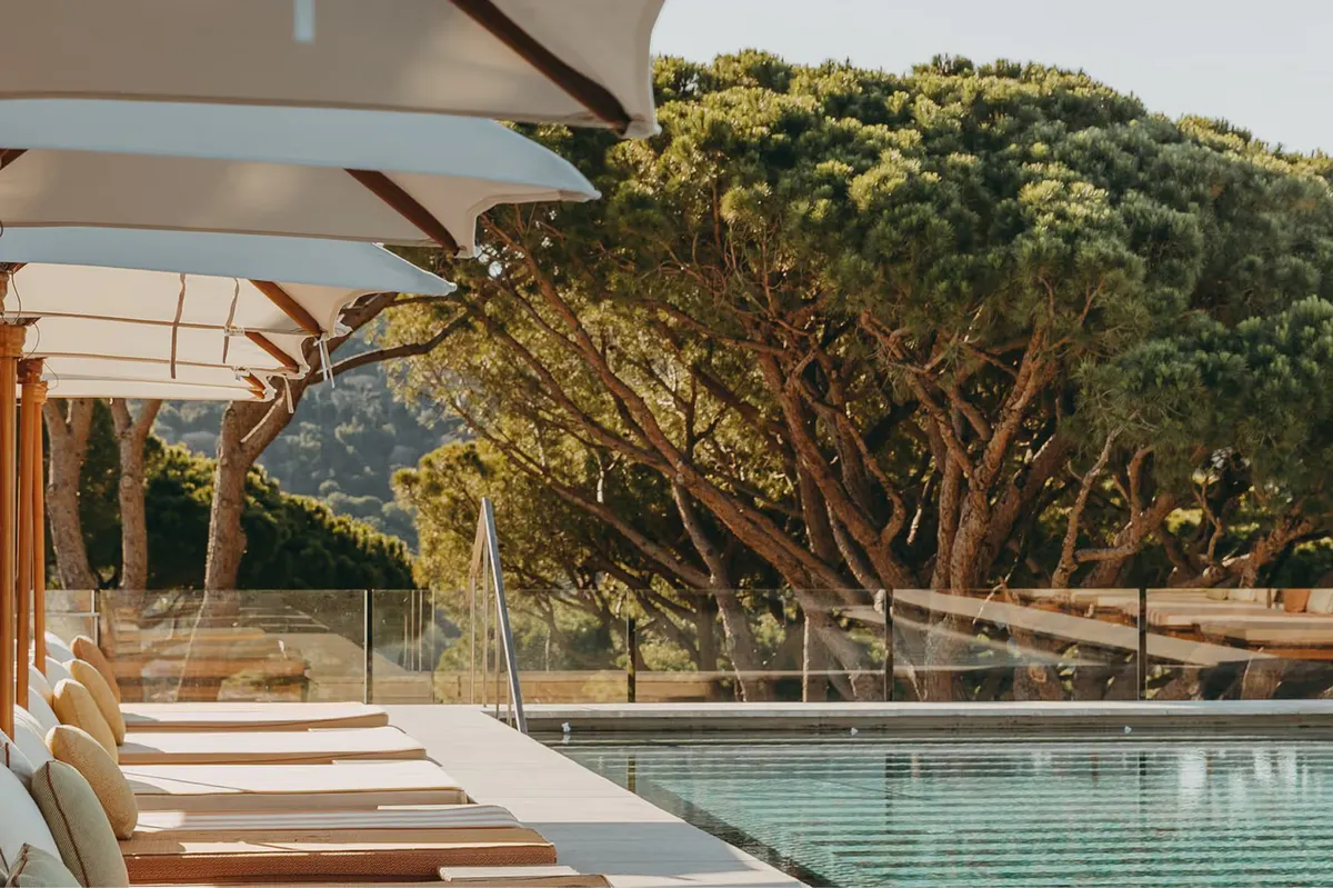 Pool deck lounge area with wooden pergola and sea view