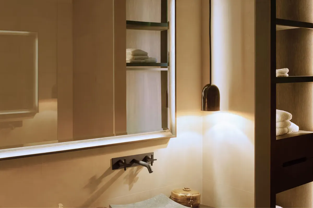 Modern vanity with illuminated mirror and built-in shelving in earth-toned room