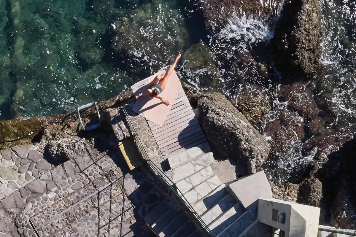 A wooden platform and stairs descending to the sea from a rocky coastal point