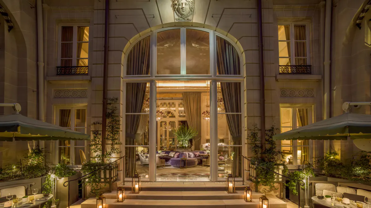 Evening view of arched stone entrance with ornate railings and warm lighting