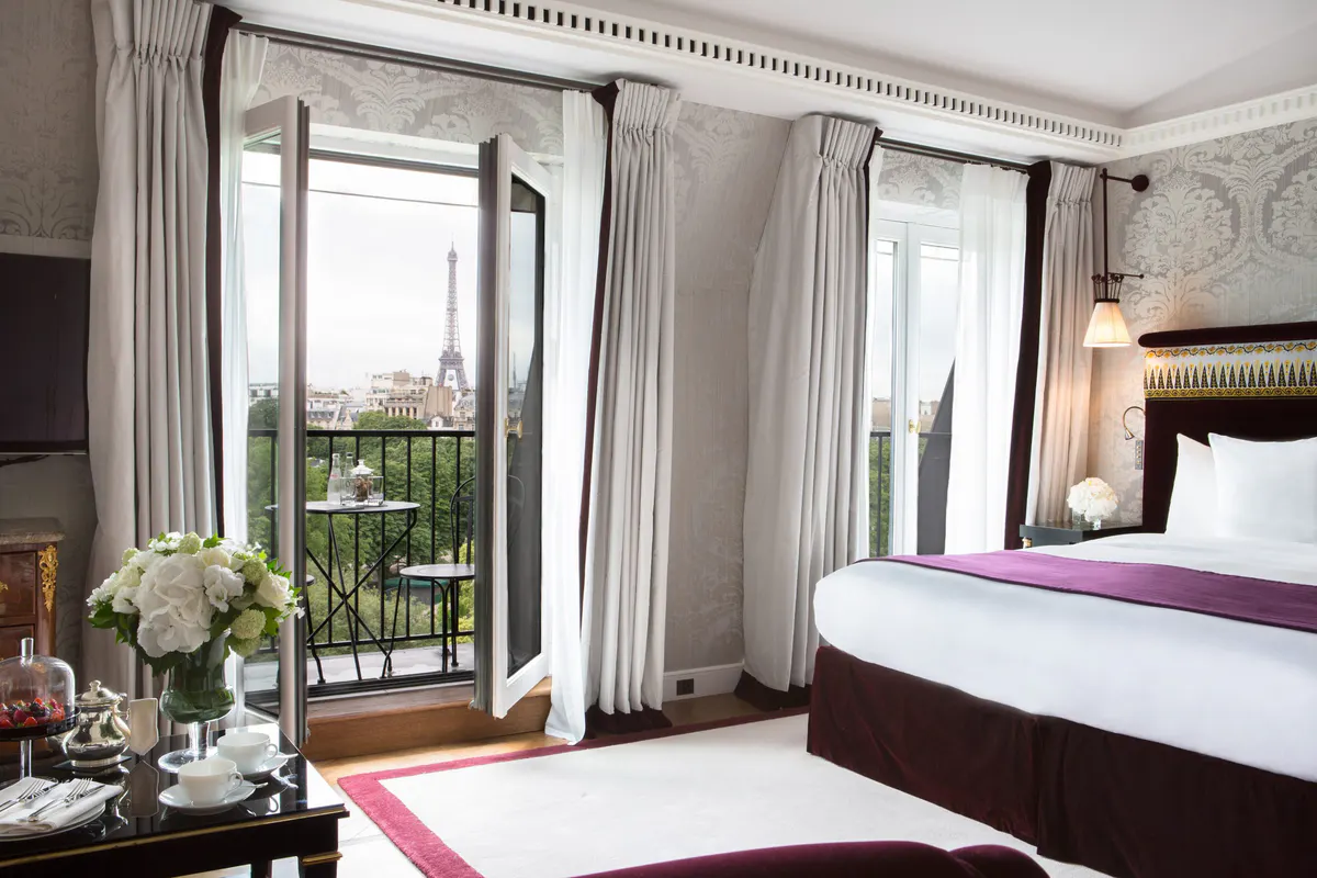 A bedroom with floor-to-ceiling windows overlooking Parisian rooftops