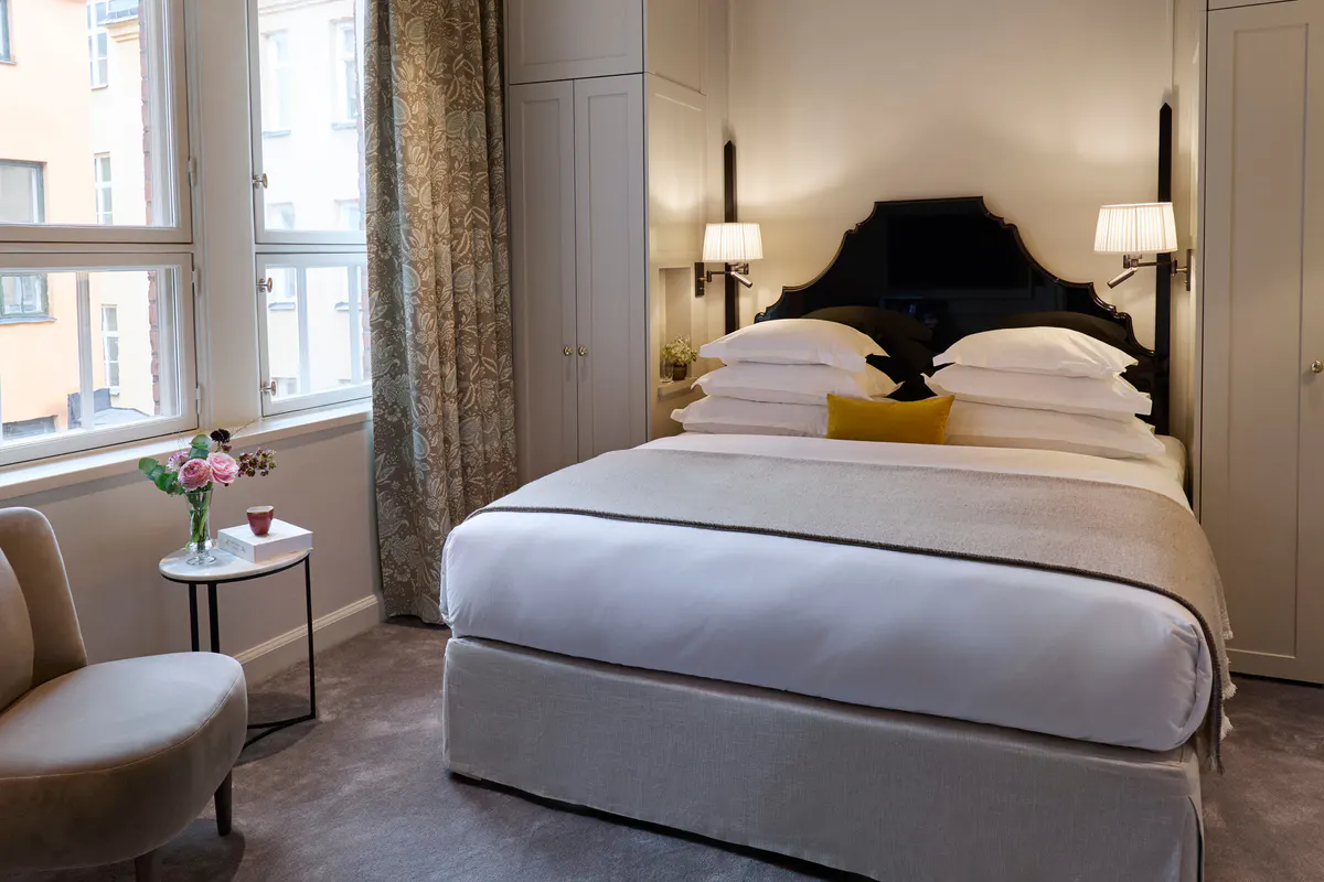 Bedroom with natural light, upholstered black headboard, and seating area by the window