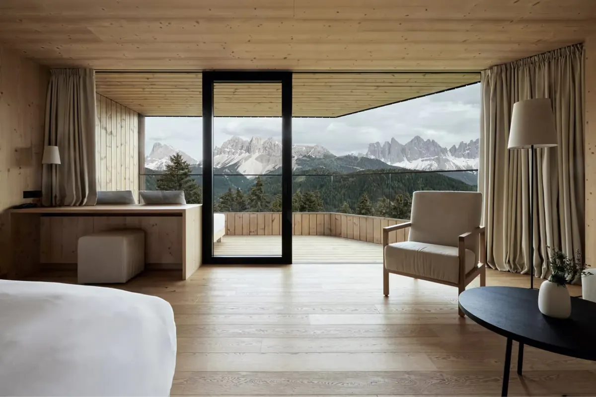 A guest bedroom with clean lines, light color palette, and a window overlooking the surrounding landscape