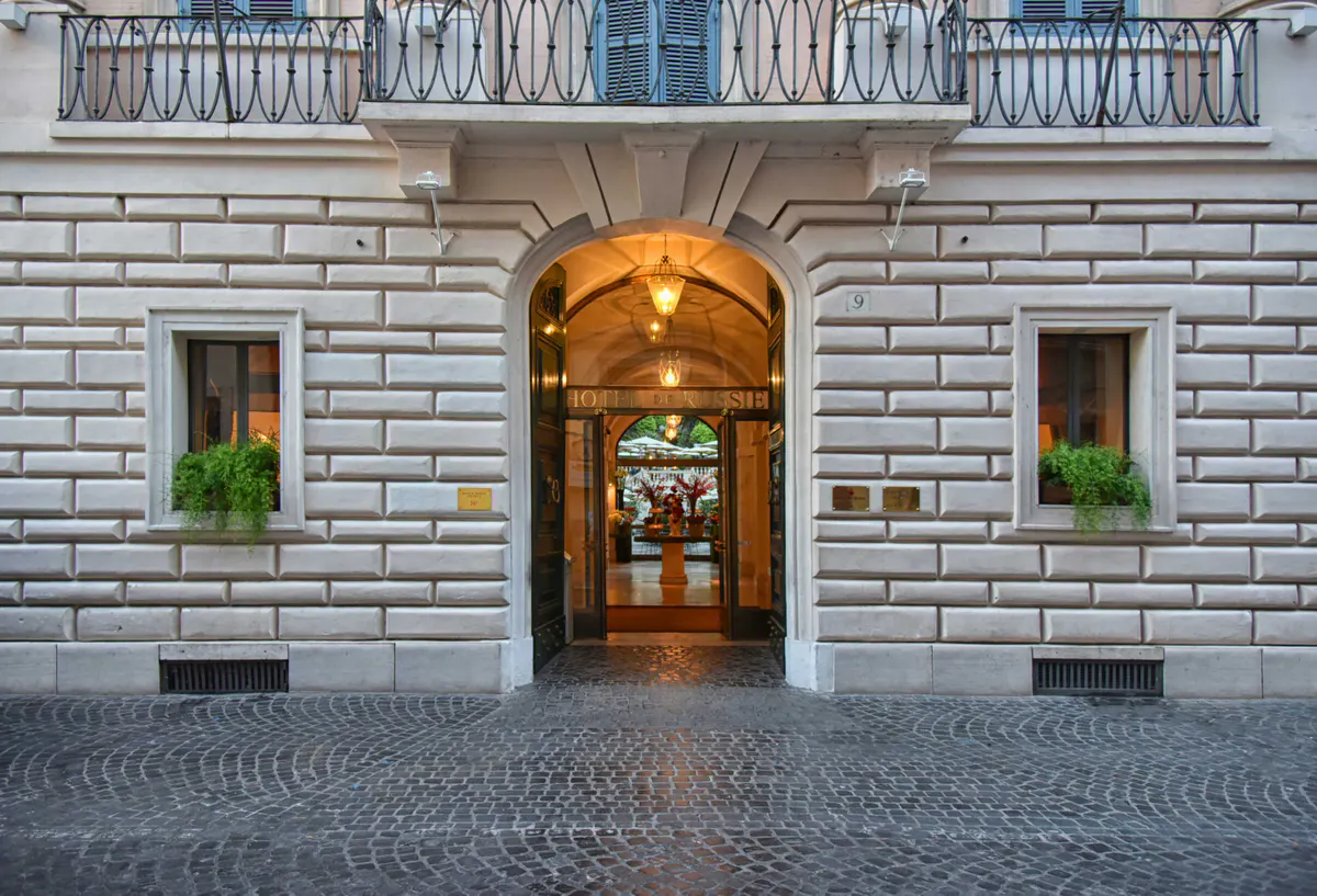 Arched palazzo entrance with warm lighting and potted plants at street level