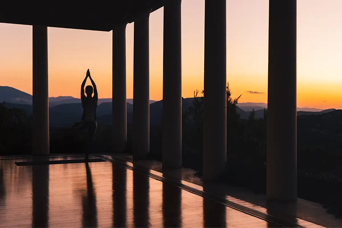 Person in yoga pose at sunset with columned structure framing