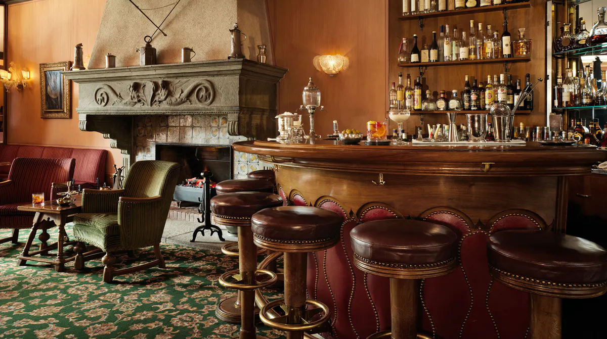 Bar lounge with wood paneling, fireplace, and seated guests in warm lighting