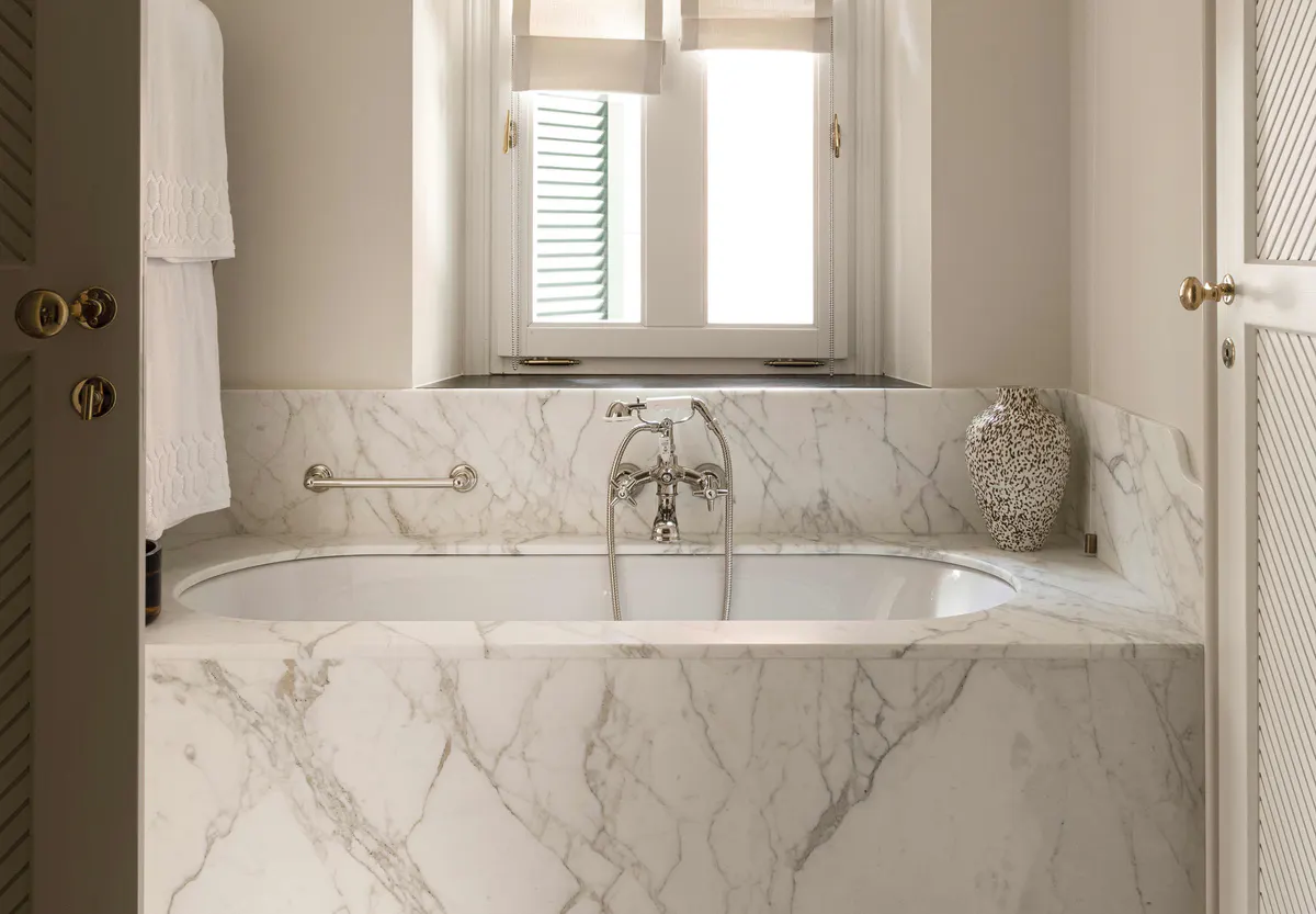 Marble bathroom with arched window and white fixtures