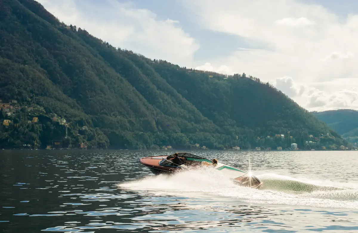 A person paddleboarding on blue lake water with forested mountains in background