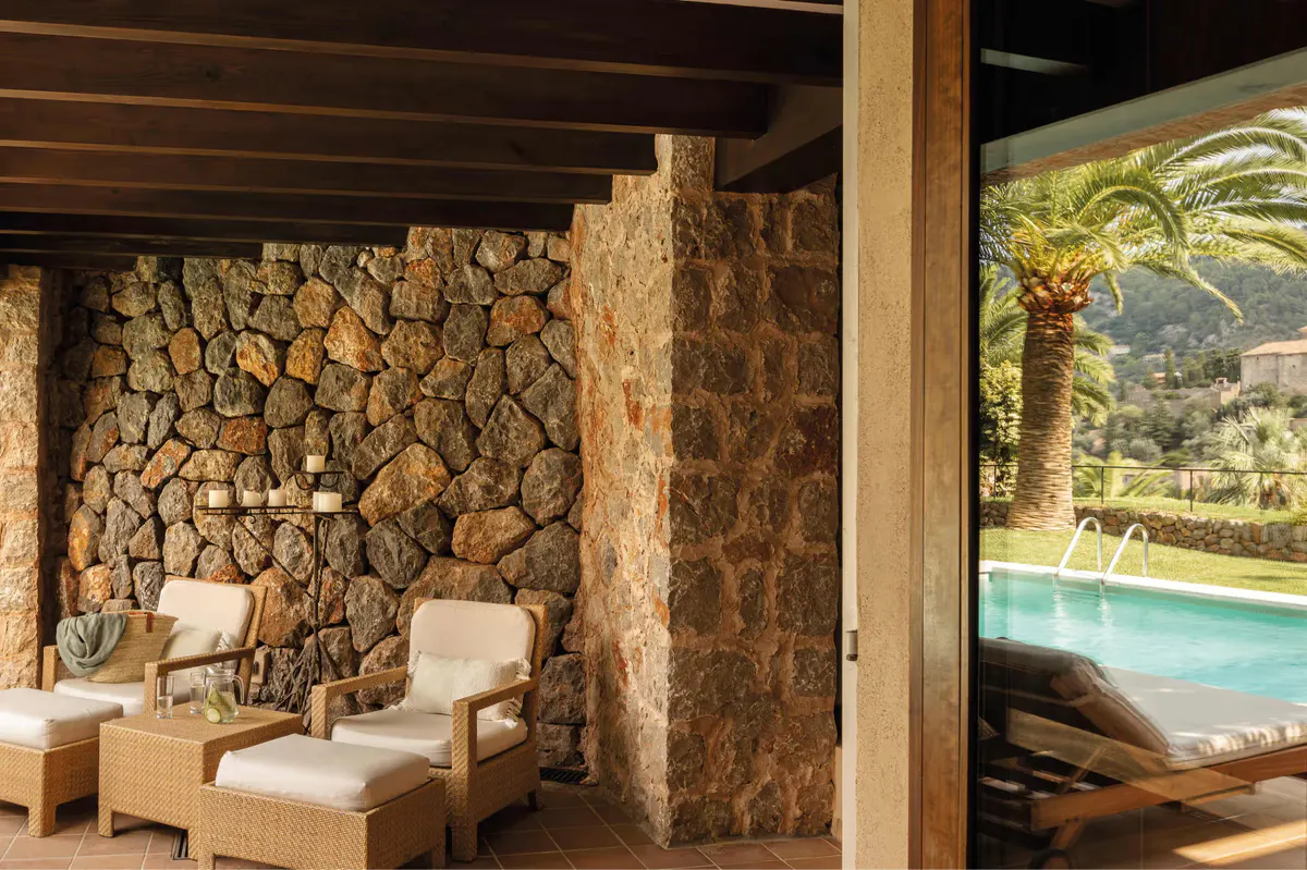 Suite alcove with stone walls, cream lounge chairs, wooden ceiling, and pool view