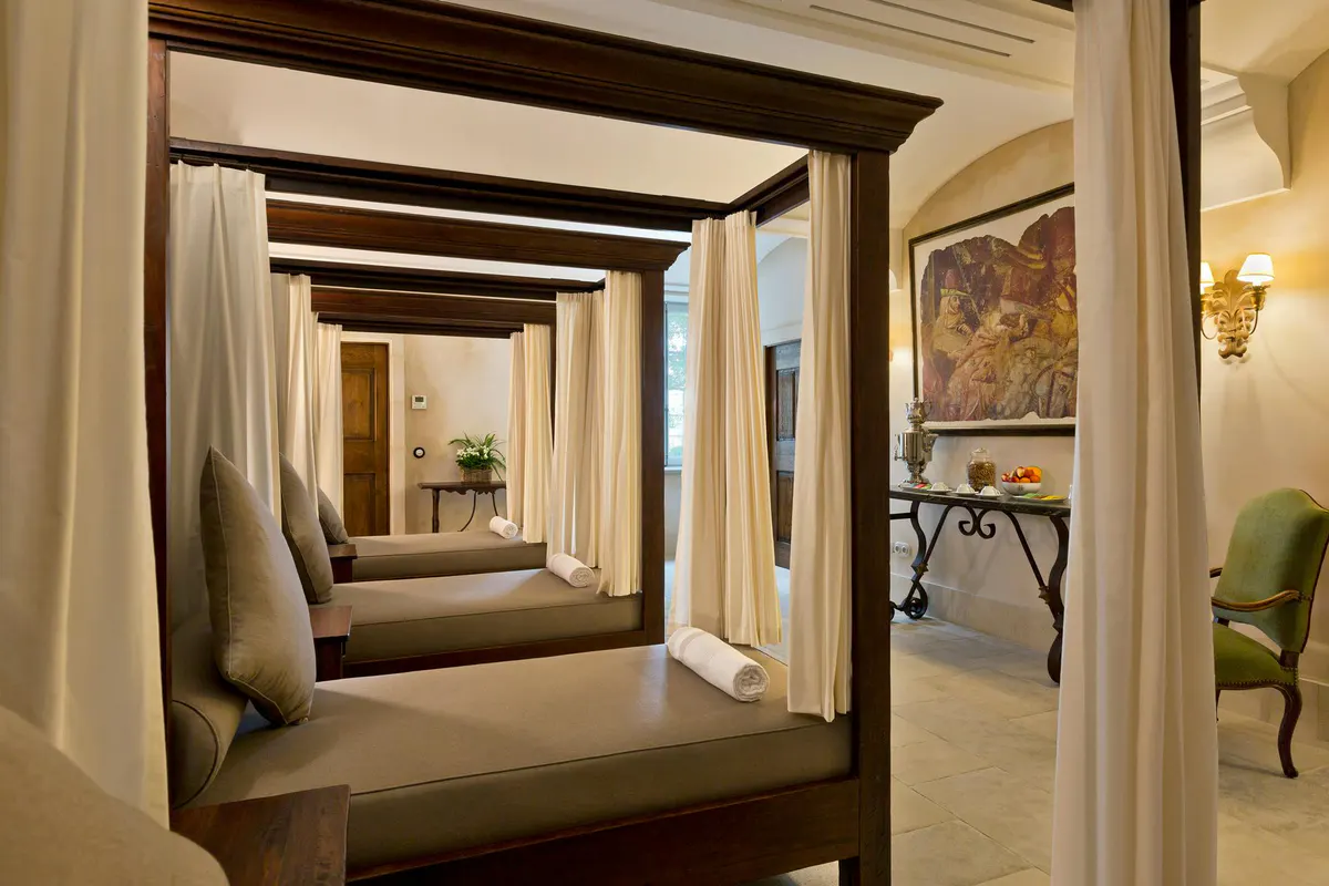 Arched stone colonnade with wall sconces and geometric ceiling detail