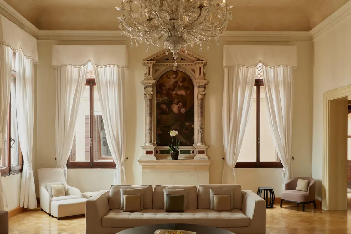 A neoclassical sitting room with symmetrical arched niches, white painted panels, cream upholstered seating, and a crystal chandelier