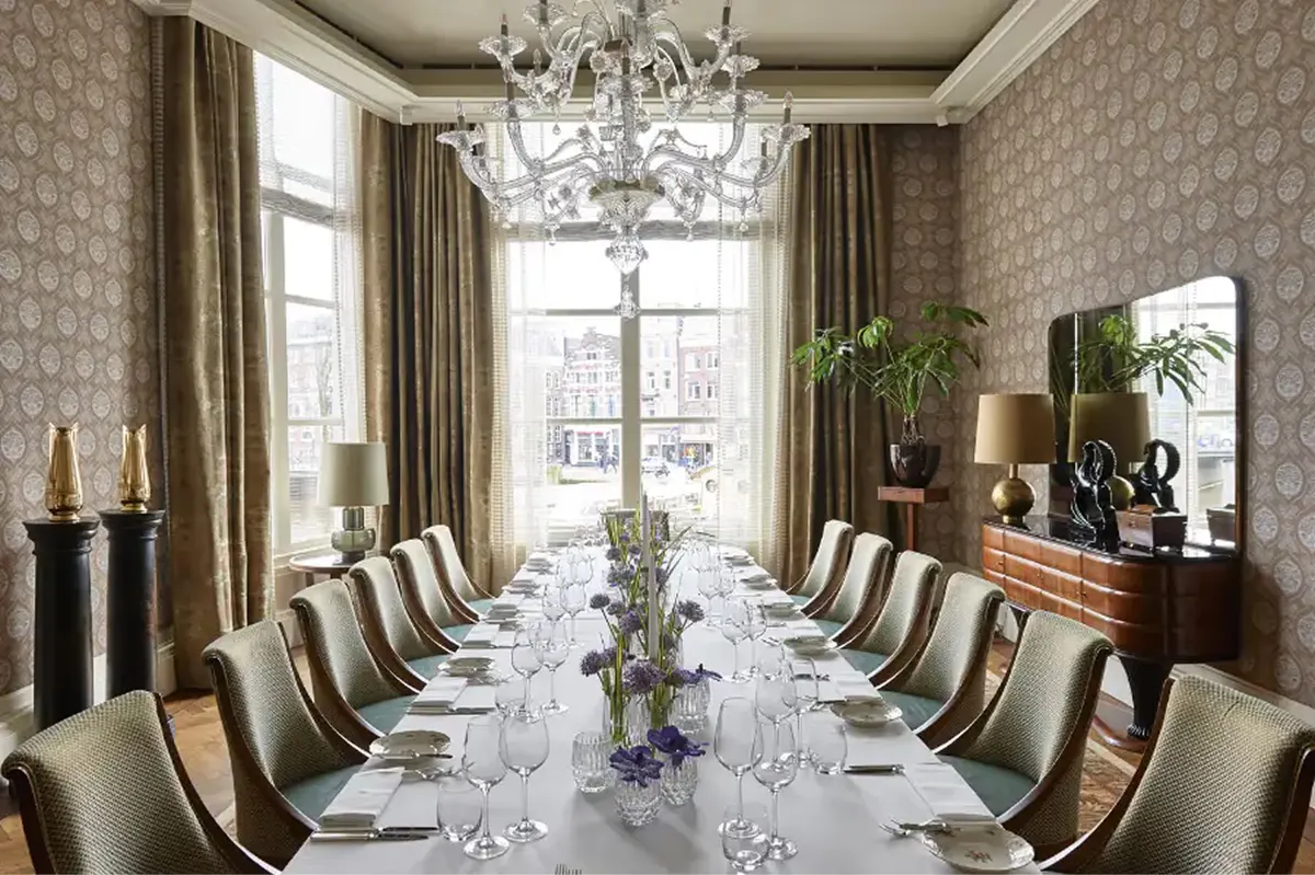 Formal dining room with long table, high ceilings, and traditional artwork on walls