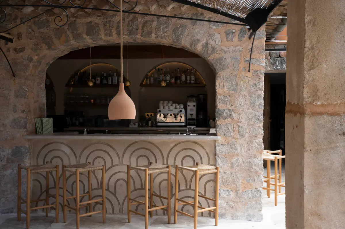 Bar counter with terracotta tile work, bottle shelving, and hanging pendant light fixture