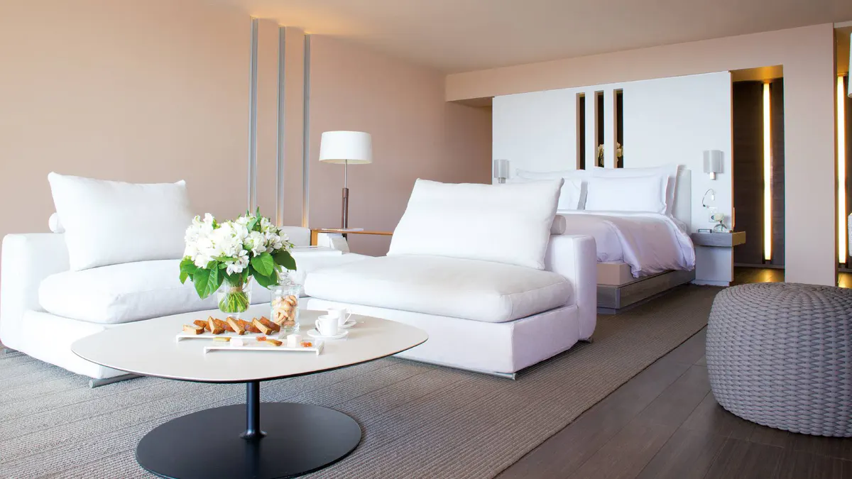 Modern suite living area with white and gray furniture and wood table