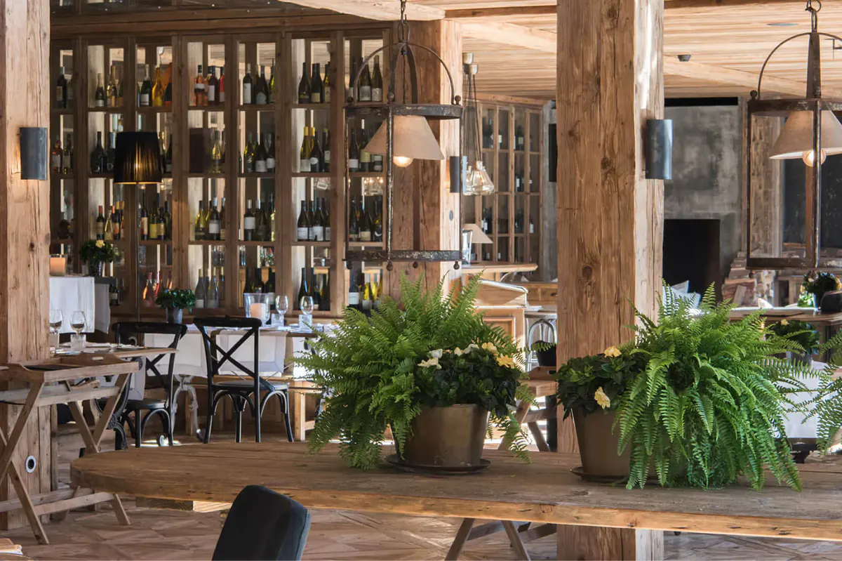 Wooden dining area with wine bottles on shelves and fresh produce at table center