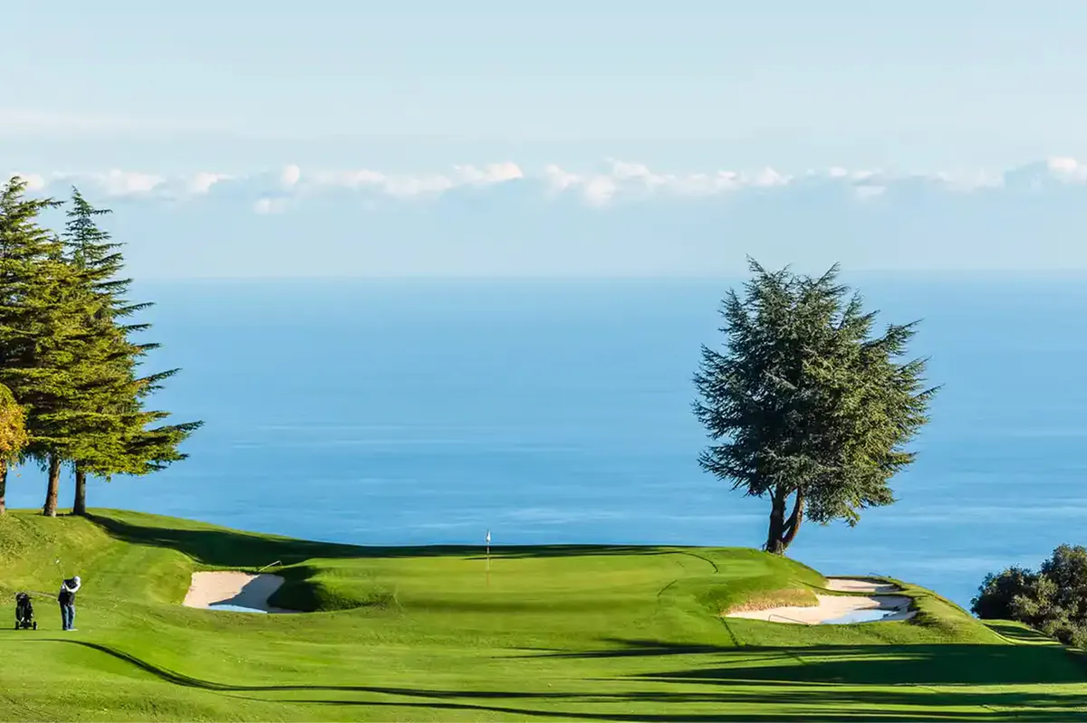 Golf course fairway with green landscape and distant sea horizon