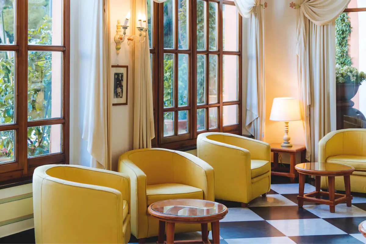A sitting room with yellow armchairs, wood-framed doors, and soft natural light