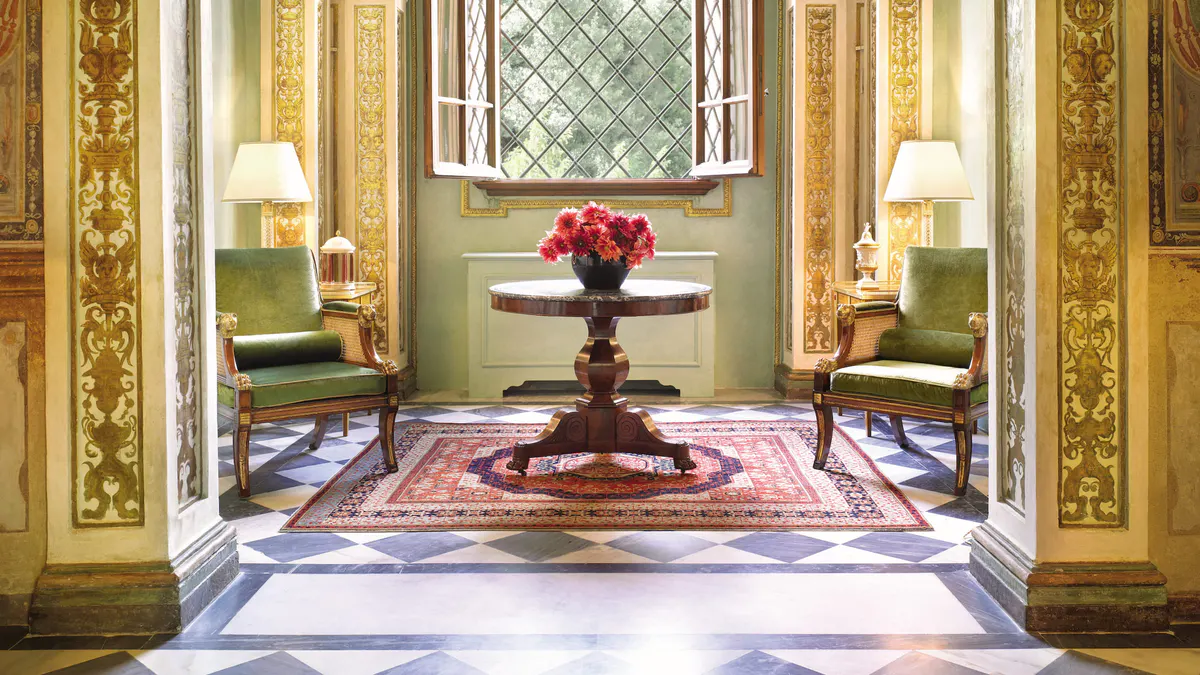 Symmetrical entryway with pale sage walls, archways, and a marble floor with burgundy inlay