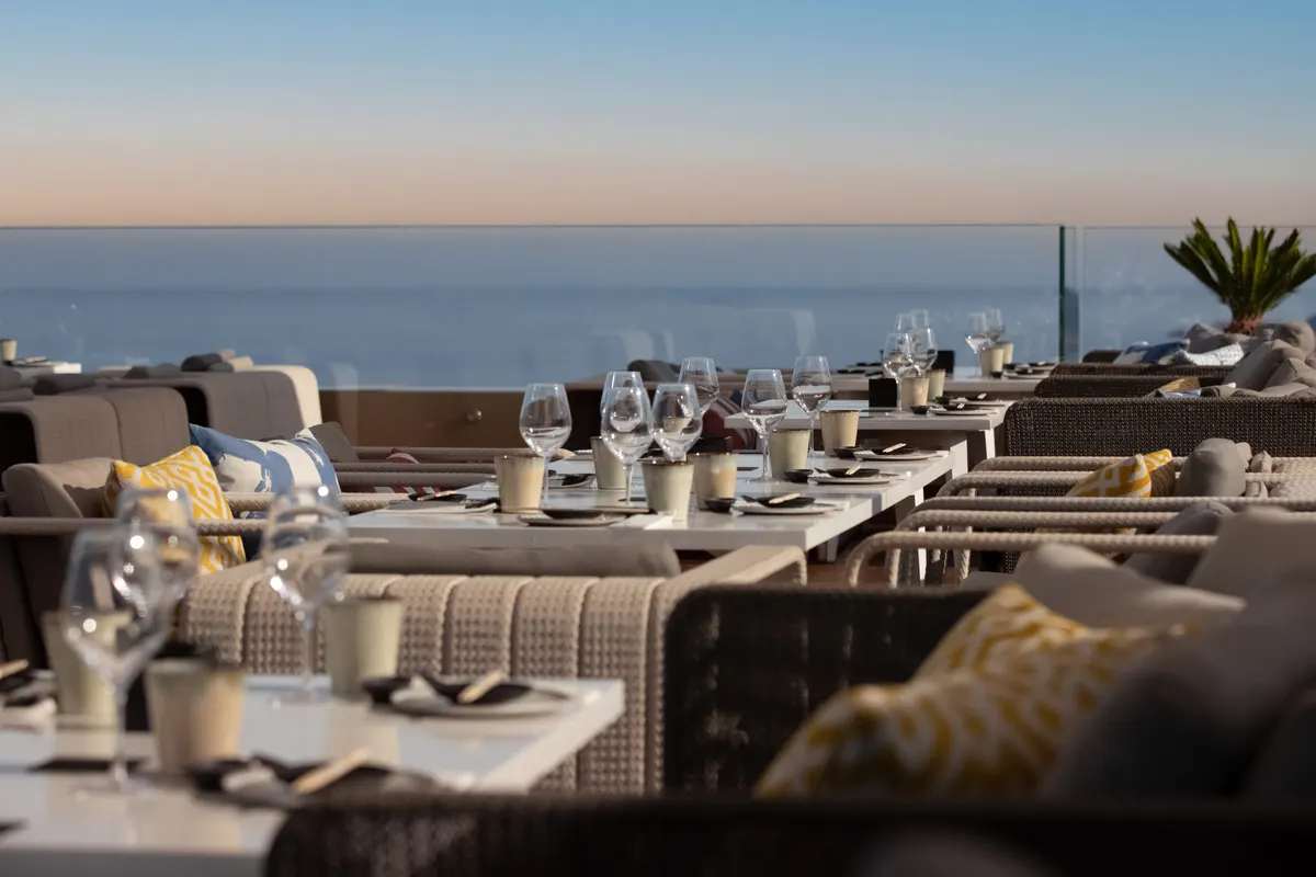 Oceanside dining terrace at sunset with white table settings