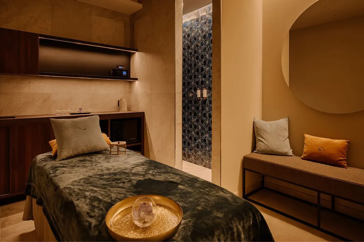 A lounge with warm lighting, sculptural furniture, and dark wood surfaces