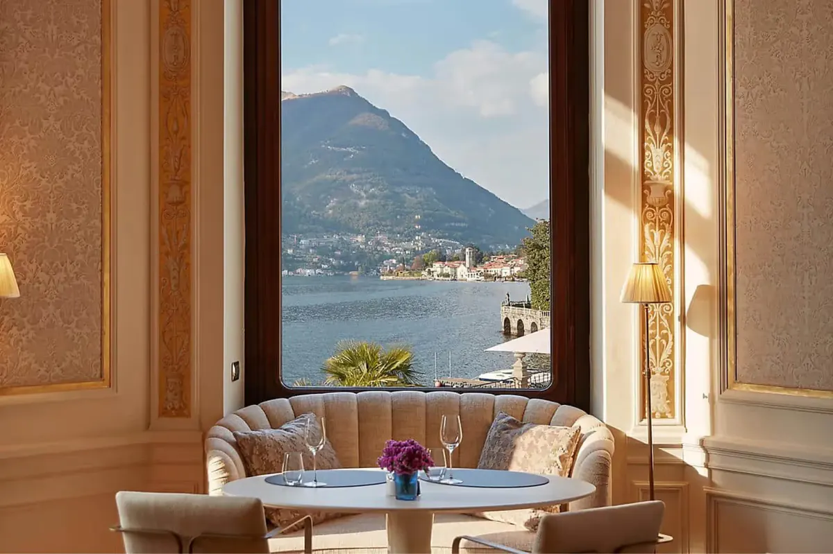Lounge room with arched windows framing lake and mountain vista, earth-toned seating