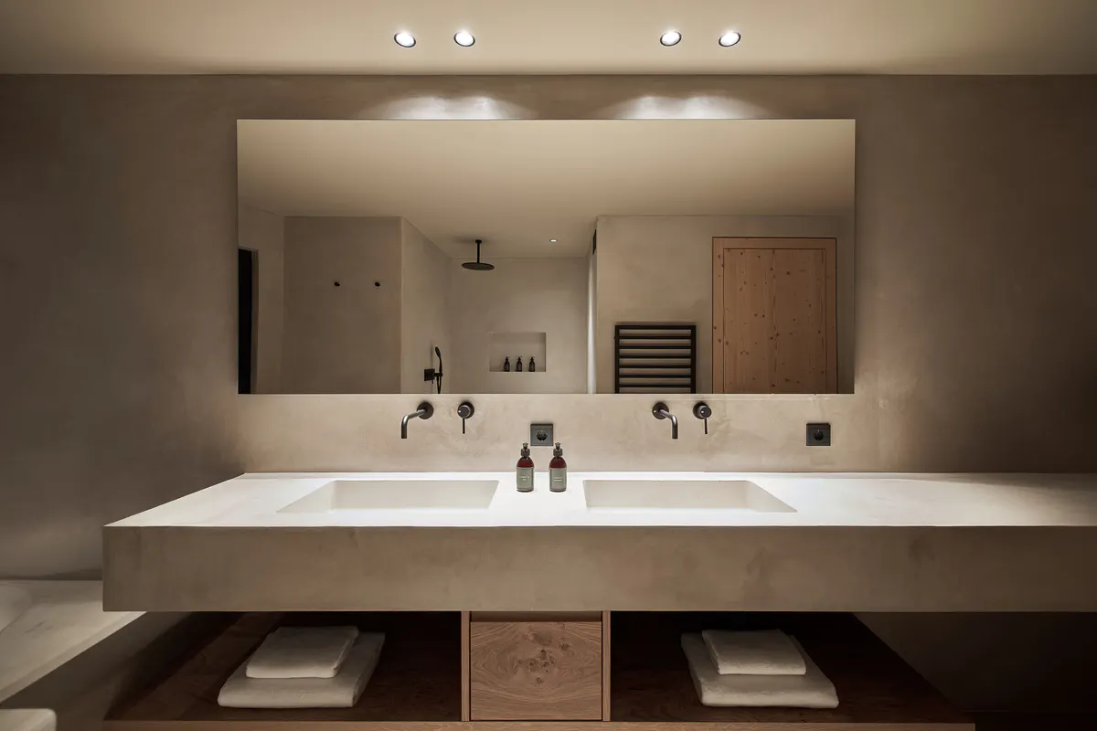 A residential suite entry with modern furnishings, neutral palette, and mountain backdrop through glass