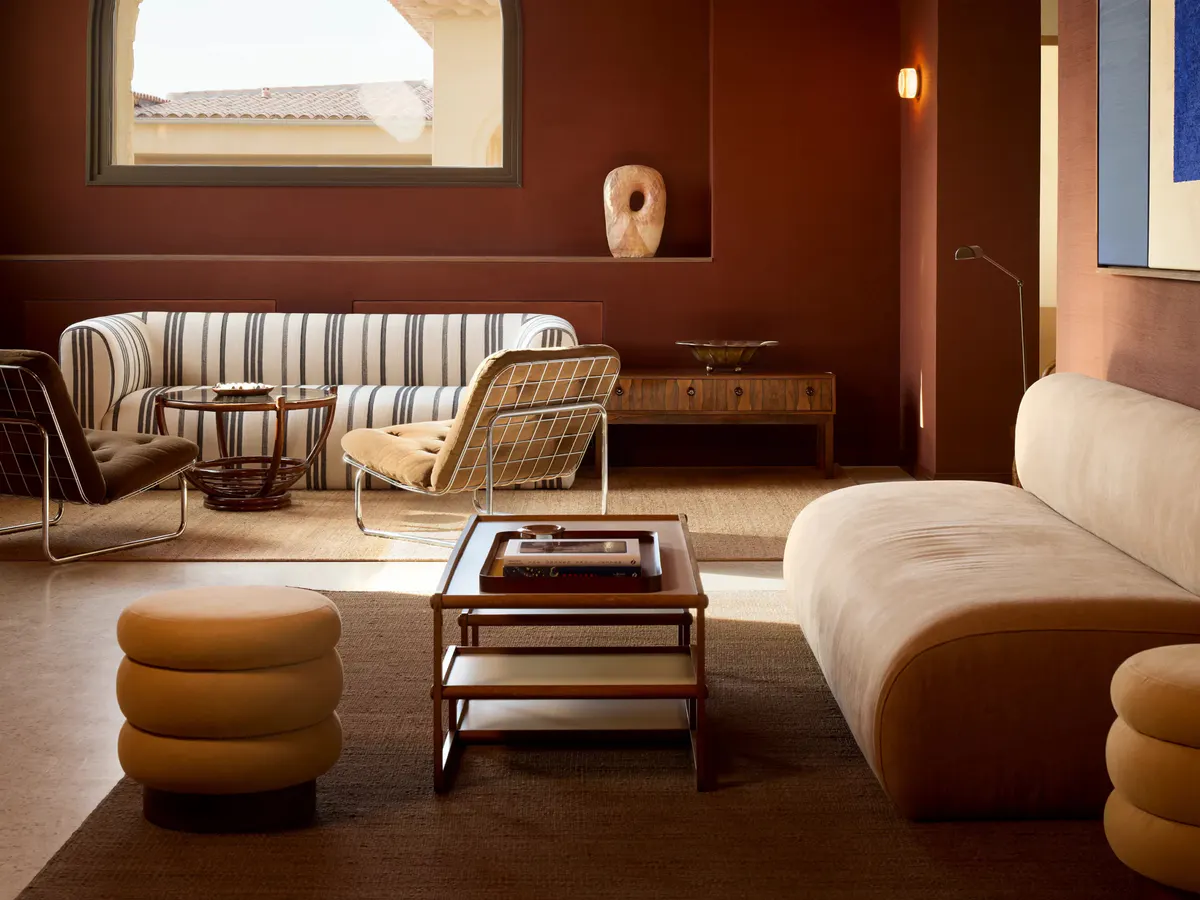 A terracotta lounge pairs a striped sofa with wire frame chairs and a marble topped table