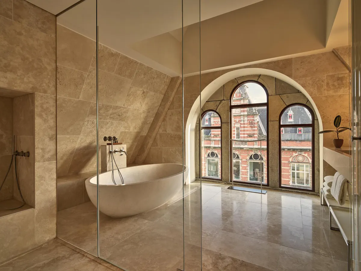 Contemporary bathroom with freestanding white soaking tub, arched windows framing city views
