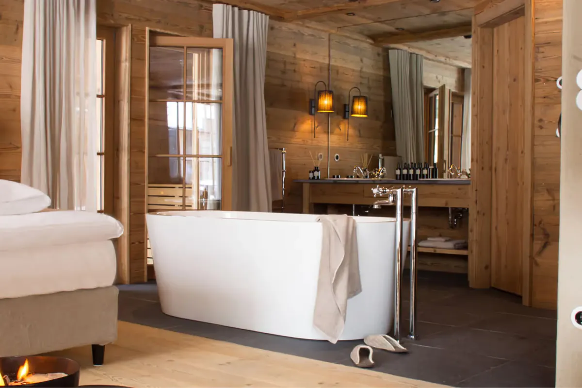 Wooden bedroom with a freestanding white soaking tub beside the bed