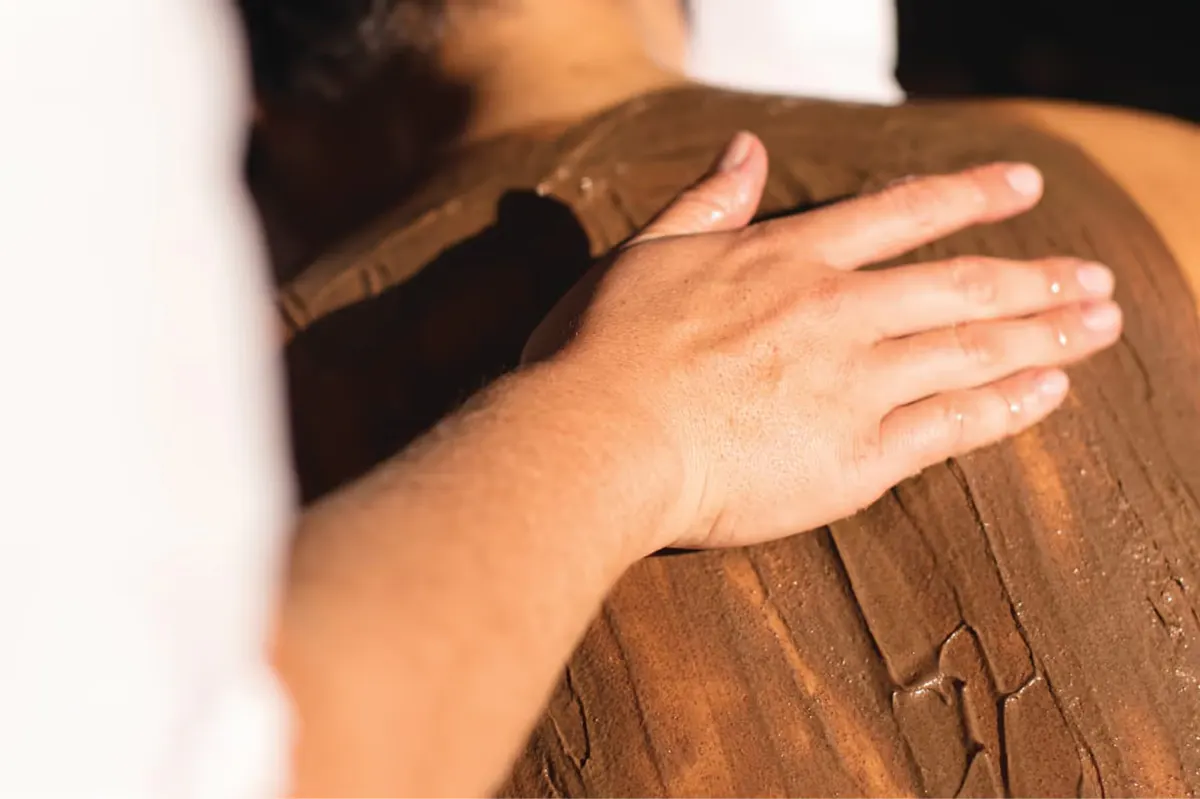 Hands demonstrating massage technique on a client’s arm during spa treatment