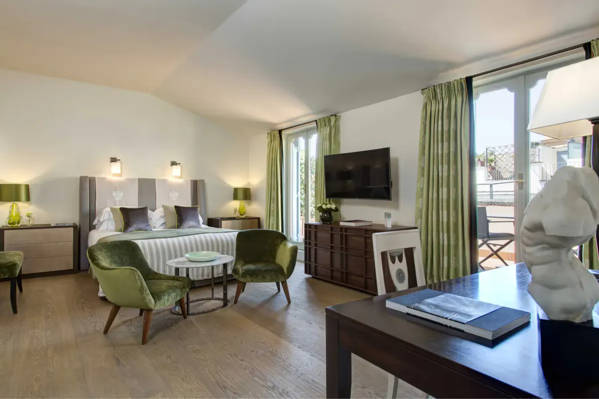 Bedroom suite with green velvet seating, striped bedding, and glass doors to a terrace