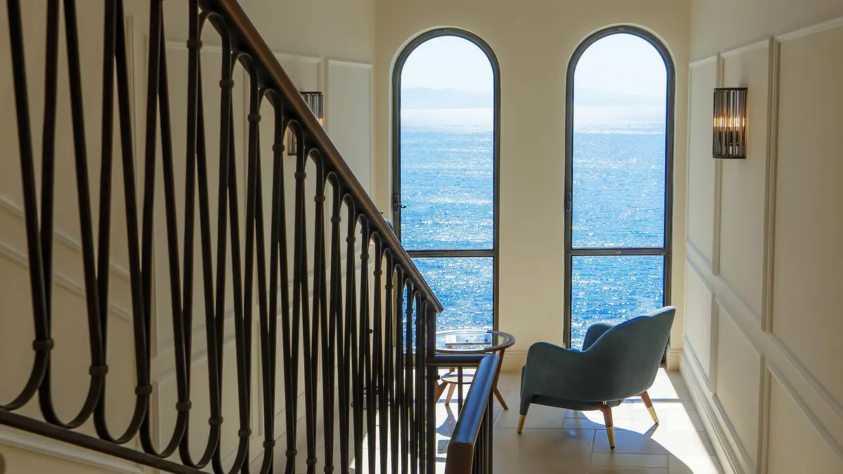 Stairwell with black railings framing arched windows overlooking the sea