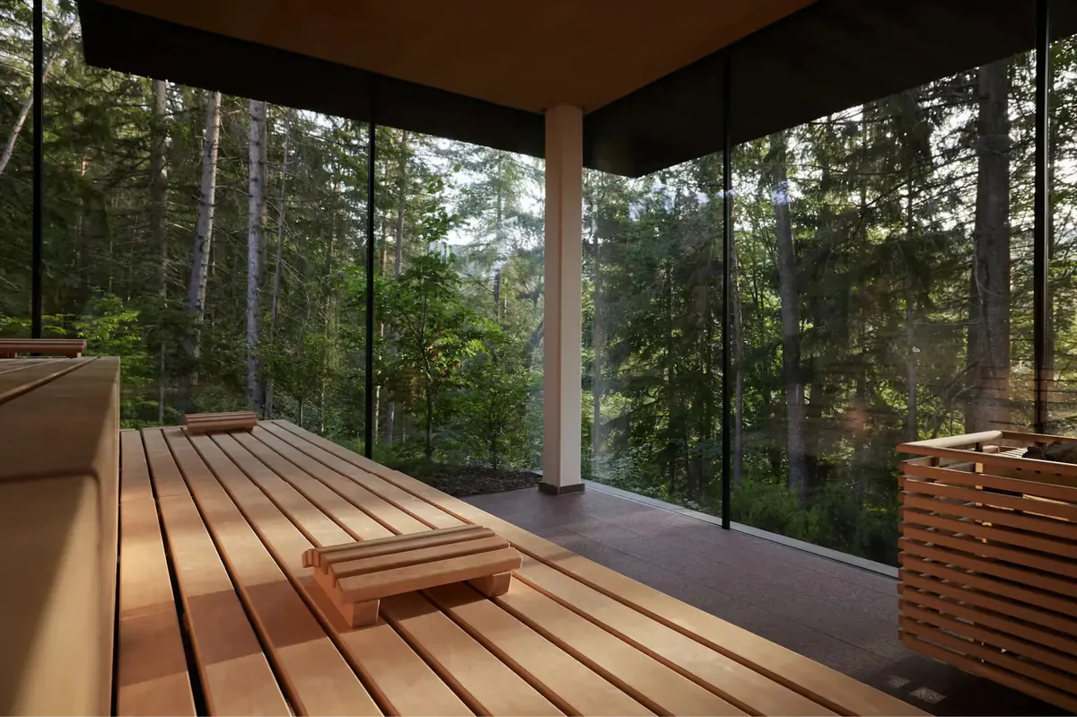 Wooden deck terrace with benches under a covered structure overlooking dense forest